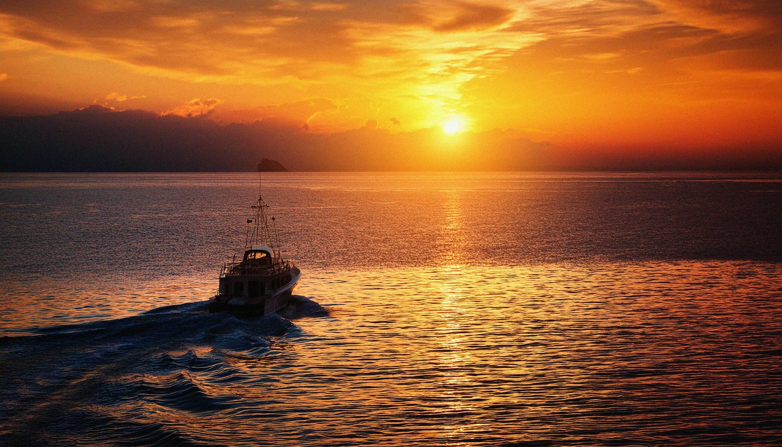 Boat crossing the sea at golden sunset
